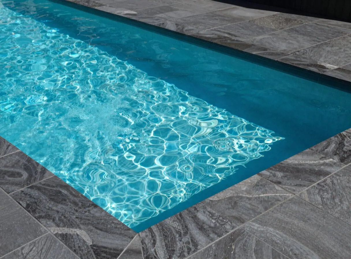 Piscină cu apă turcoaz, bordură și plajă din piatră gri